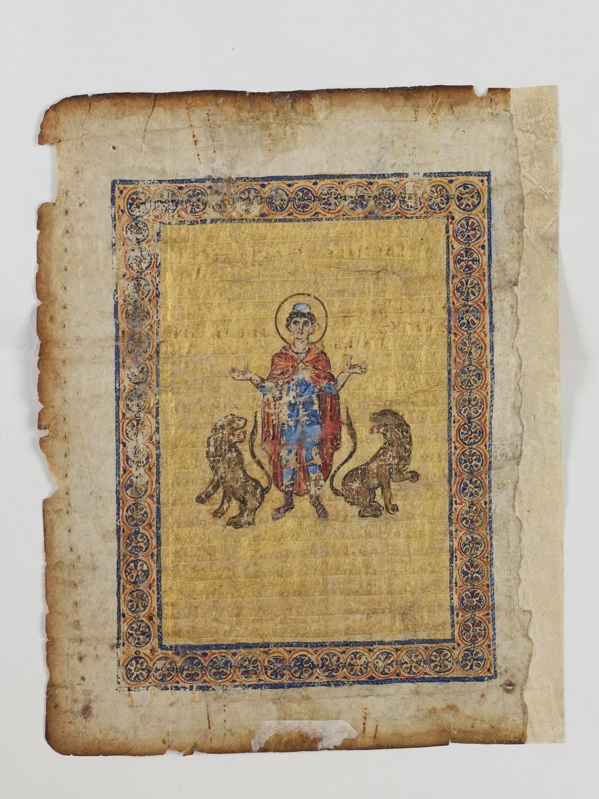 A leaf of the Archimedes Palimpsest: a scorched parchment page with a gold-ground painting of a haloed figure between two lions inside a decorated border