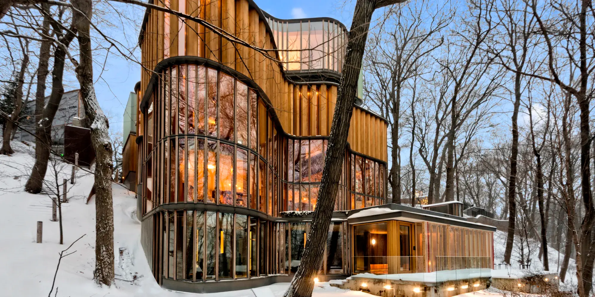 Integral House at dusk in winter — glass and oak curtain wall glowing from within