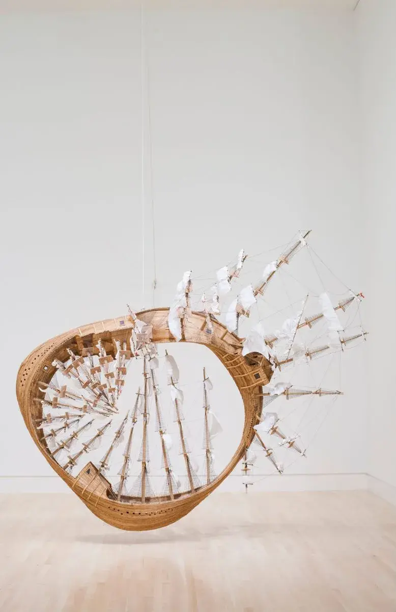 Close-up of Tim Hawkinson's Möbius Ship — wooden hull, masts, rigging, and white sails following the curve of the Möbius loop