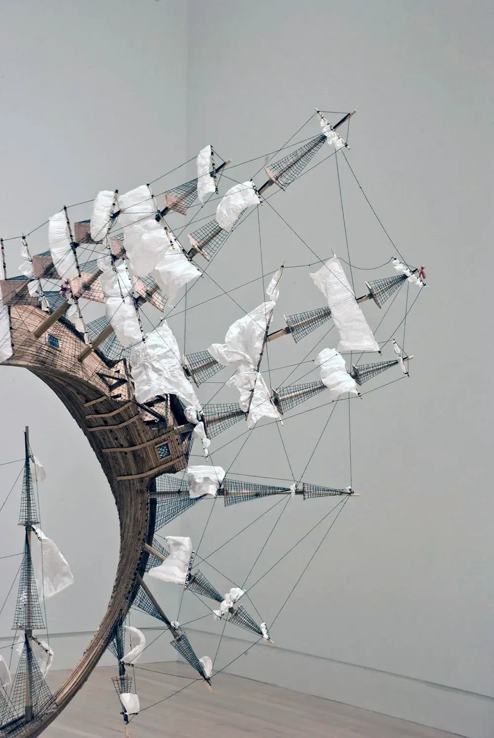 Tim Hawkinson's Möbius Ship sculpture — a wooden sailing vessel with its hull twisted into a continuous Möbius strip, suspended in a gallery